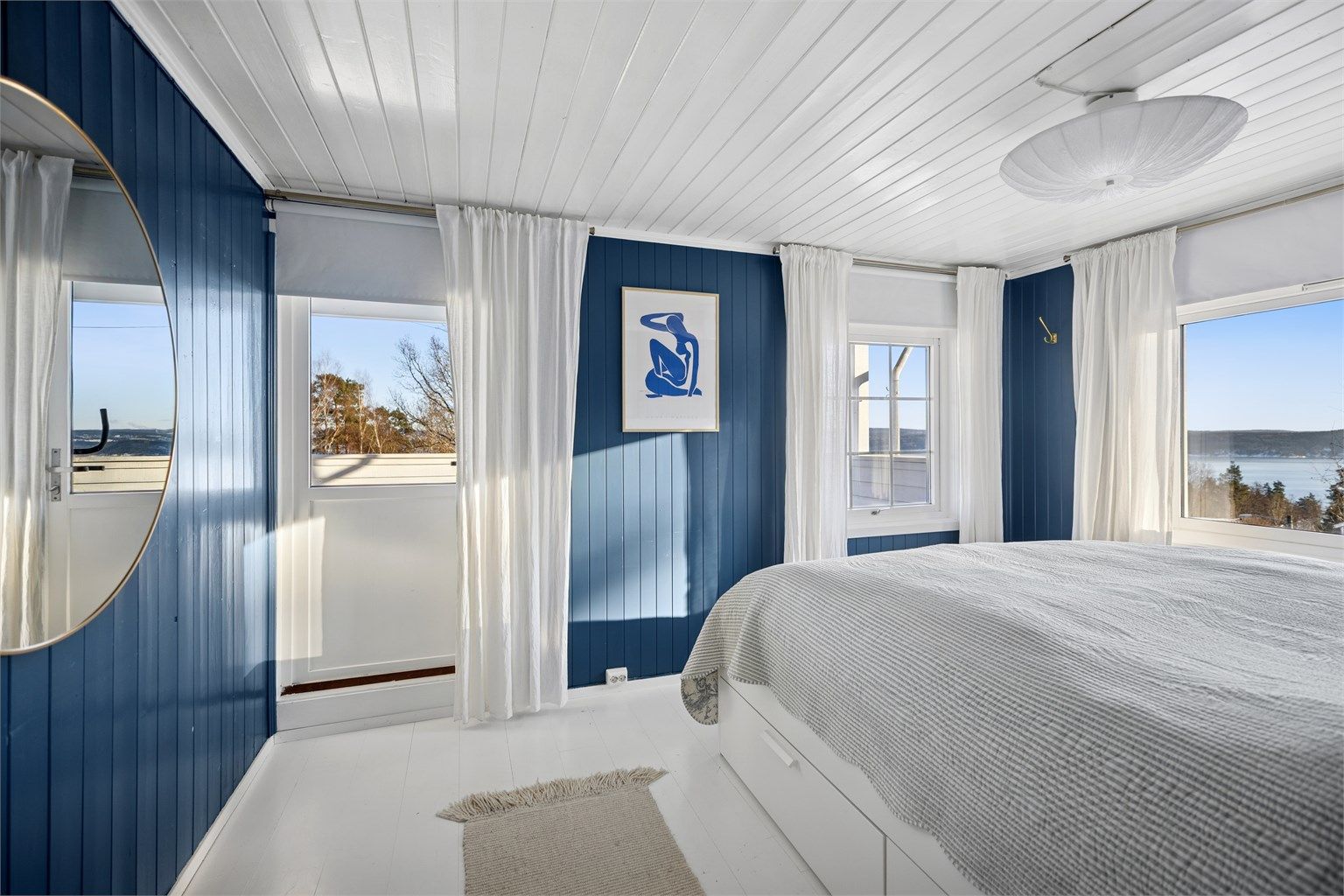 Hovedsoverommet fremstår som lyst og innbydende, med nydelig fjordutsikt og direkte utgang til en solrik takterrasse.