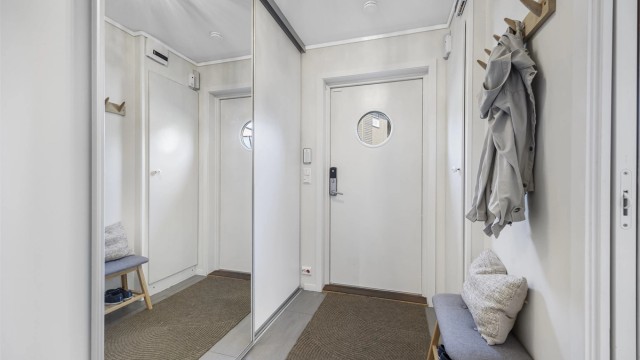 Entréen har flislagt gulv med varmekabler og god oppbevaringsplass i skyvedørsgarderobe.
