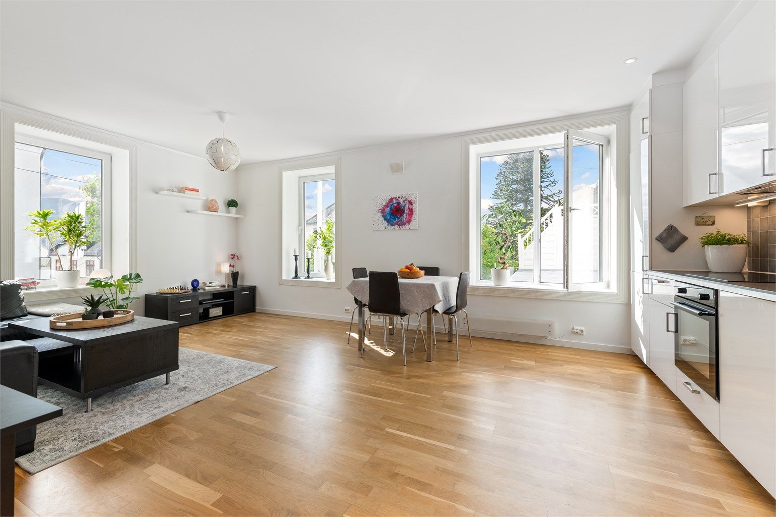 Stue og kjøkken i åpen løsning med store vindusflater som gir godt med naturlig lysinnslipp