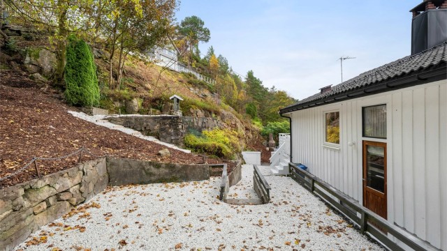 Baksiden er pent opparbeidet med singel, trapper og forstøtningsmurer.