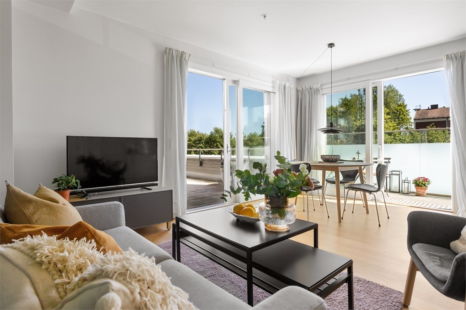 Lys og innbydende stue med store vindusflater i skyvedører.