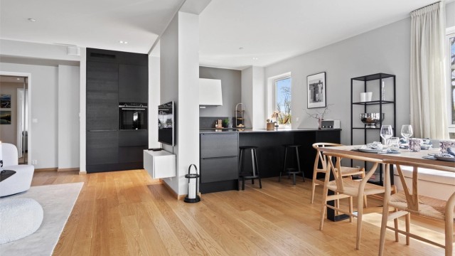 Innredningen har sorte, finerte fronter og matchende benkeplate i steinkompositt med underlimt kum i stål.