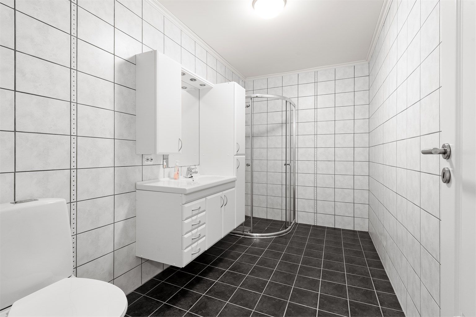 Bad i utleieleiligheten er flislagt og har en stor og romslig innredning, dusjhjørne og wc.