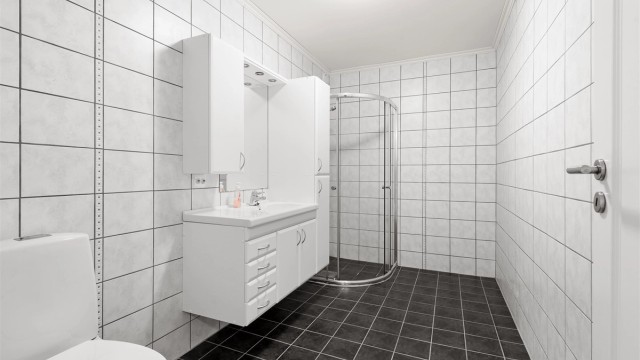Bad i utleieleiligheten er flislagt og har en stor og romslig innredning, dusjhjørne og wc.