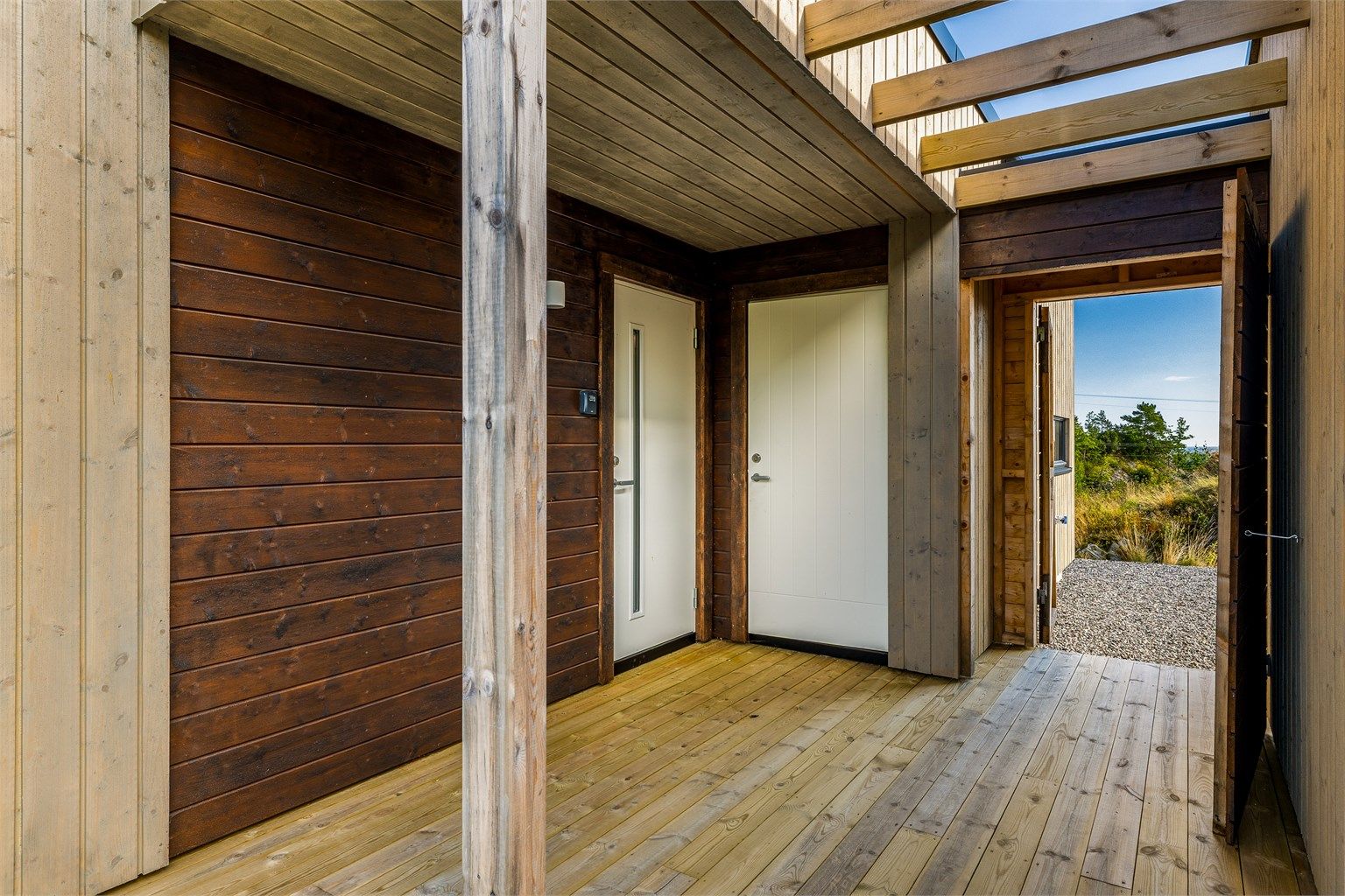 Overbygget inngangsparti med platting mellom hytte og anneks.