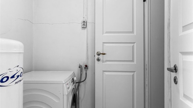 Praktisk vaskerom i underetasjen med flislagt gulv, gulvvarme og opplegg for vaskemaskin.