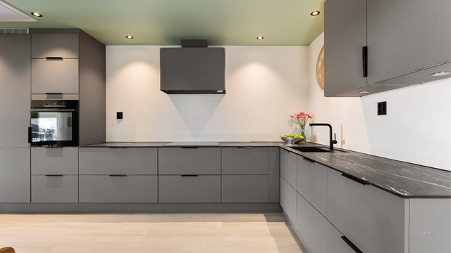 Innredningen er utstyrt med integrerte hvitevarer, inkludert komfyrer i høyskap og nedfelt induksjonstopp med komfyrvakt.