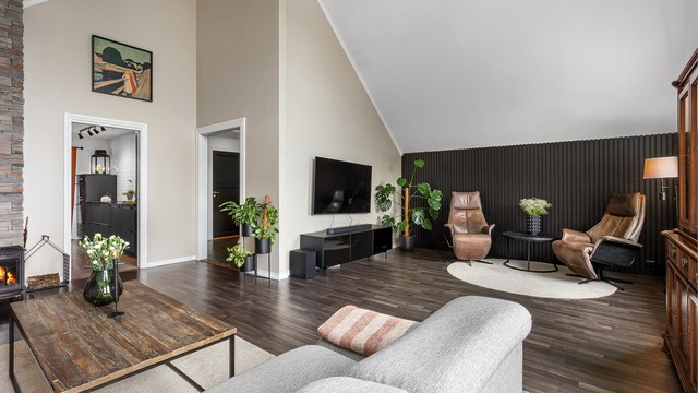 Stuen har flere soner og en moderne spilevegg som skaper en stilren overgang.