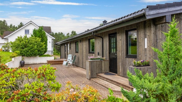 Velholdt fasade med stående trekledning, nylig etterisolert og oppgradert.