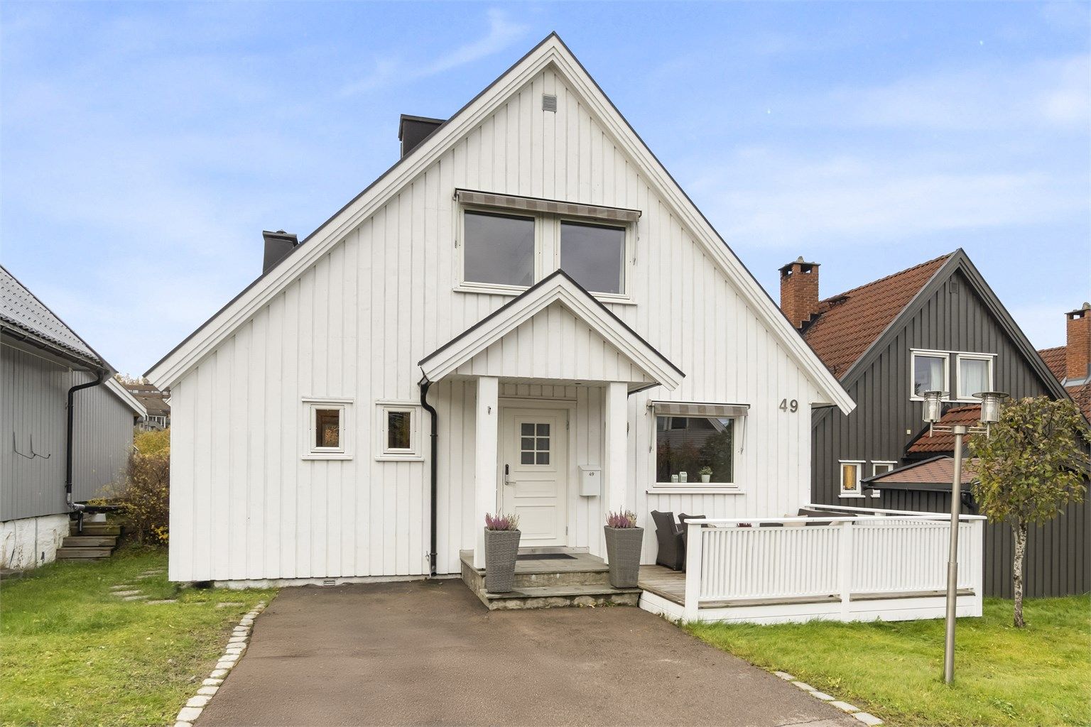 Romslig inngangsparti med en liten terrasse samt én parkeringsplass.