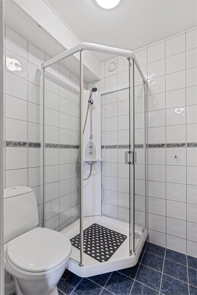 Badet har flislagt gulv med gulvvarme og et praktisk dusjkabinett.