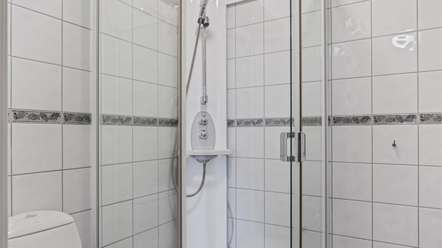 Badet har flislagt gulv med gulvvarme og et praktisk dusjkabinett.