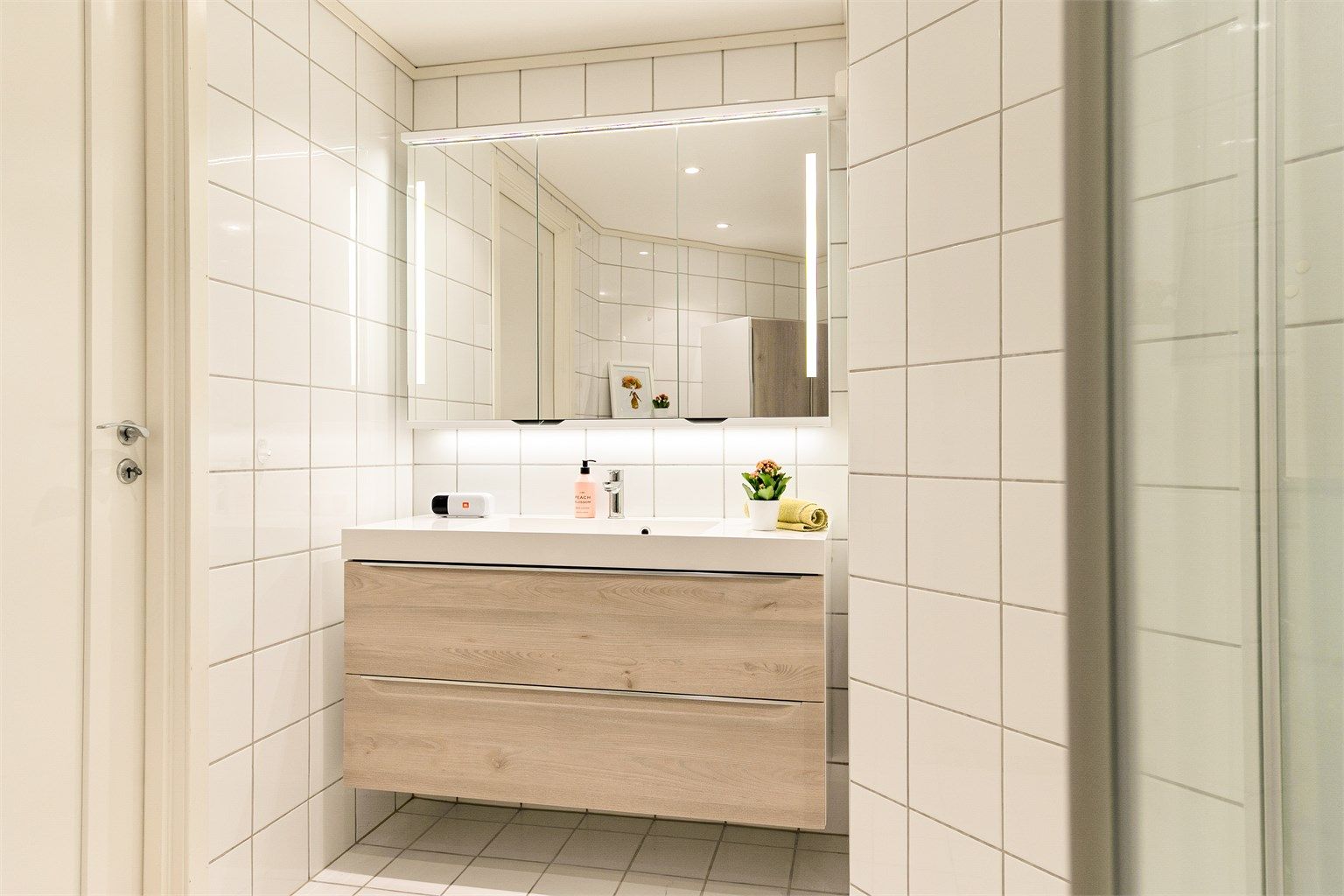 - Badet har flislagte overflater, vegghengt servantinnredning og speilskap -