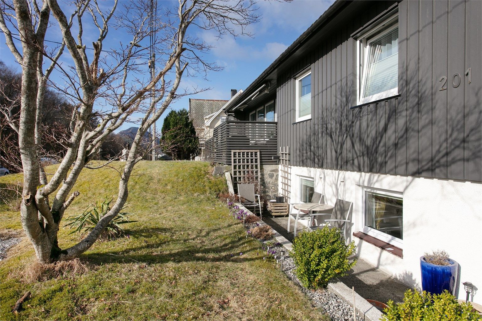 Fasade mot syd - hagen er opparbeidet med plen, beplantinger og gruslagt parkeringsareal