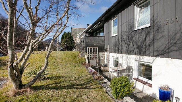 Fasade mot syd - hagen er opparbeidet med plen, beplantinger og gruslagt parkeringsareal