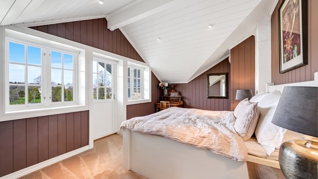 Hovedsoverommet har en lun atmosfære med heldekkende teppe på gulvet og malte panelvegger.
