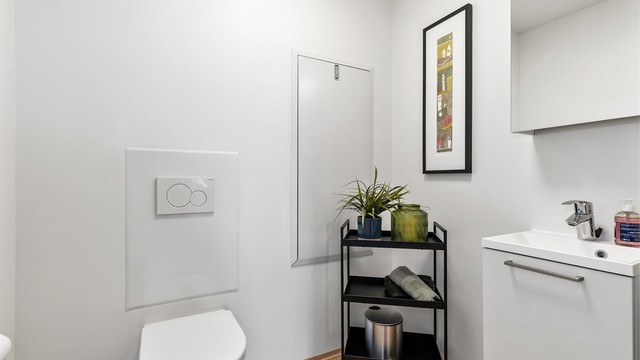 Separat toalettrom med vegghengt toalett, servant og vannbåren gulvvarme.