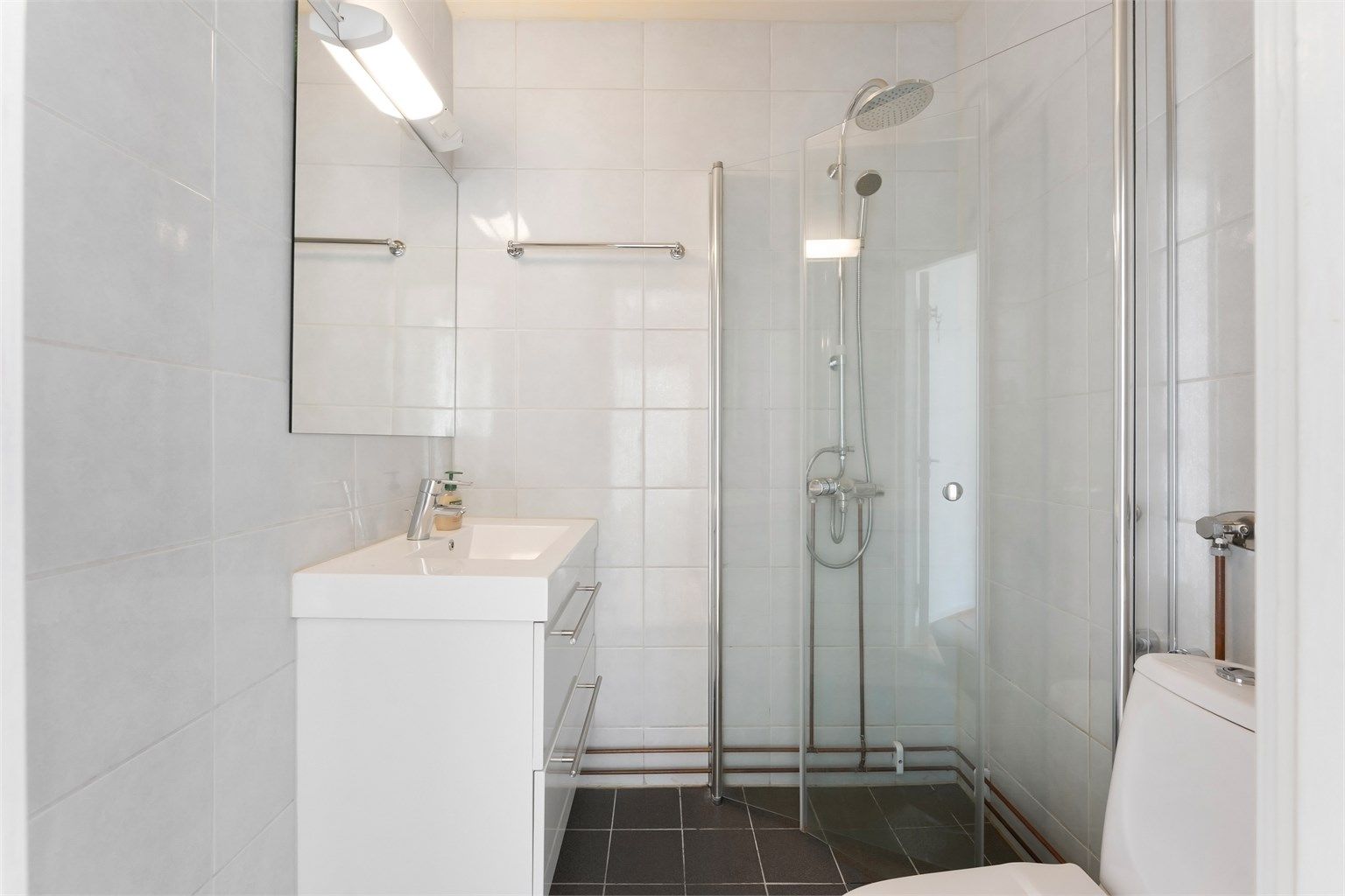 Flislagt bad fra 2012 med vegghengt servantinnredning og dusjhjørne med regndusj.