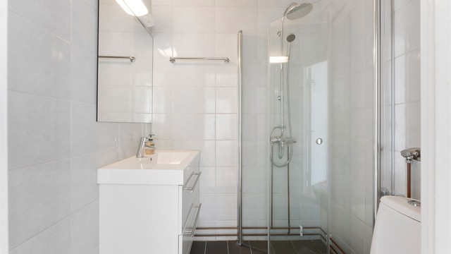 Flislagt bad fra 2012 med vegghengt servantinnredning og dusjhjørne med regndusj.