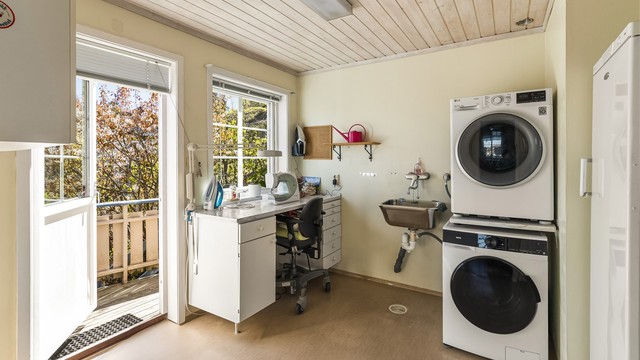 Praktisk vaskerom med opplegg for vaskemaskin og utgang til en østvendt balkong.