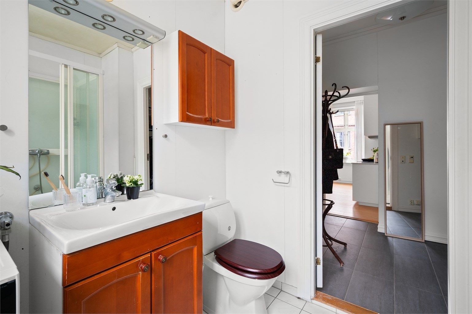 Innredningen består av gulvmontert toalett, skap for oppbevaring, servant med underskap i tillegg til dusjkabinett.