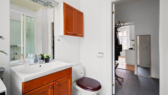 Innredningen består av gulvmontert toalett, skap for oppbevaring, servant med underskap i tillegg til dusjkabinett.