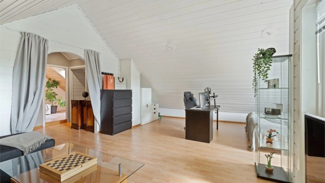 Rommet har malt panel i himling og laminat på gulvet.