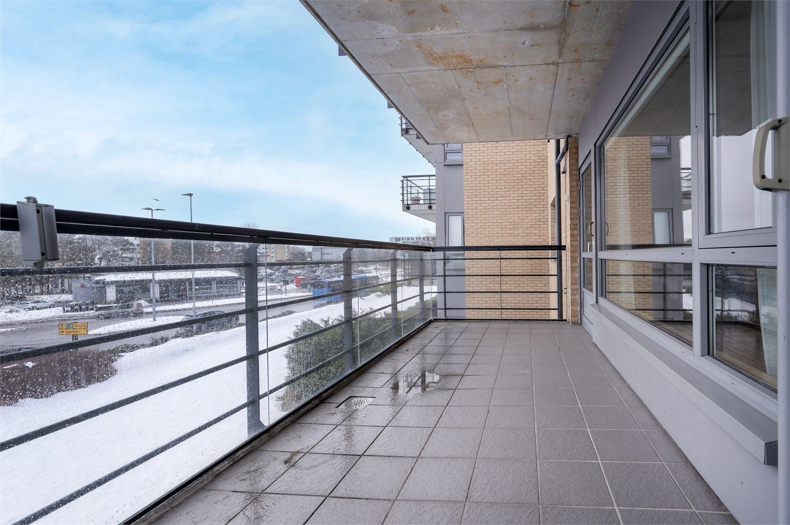 Terrasse mot syd med rekkverk av glass og stål. Her er det også utvendig stikkontakt 