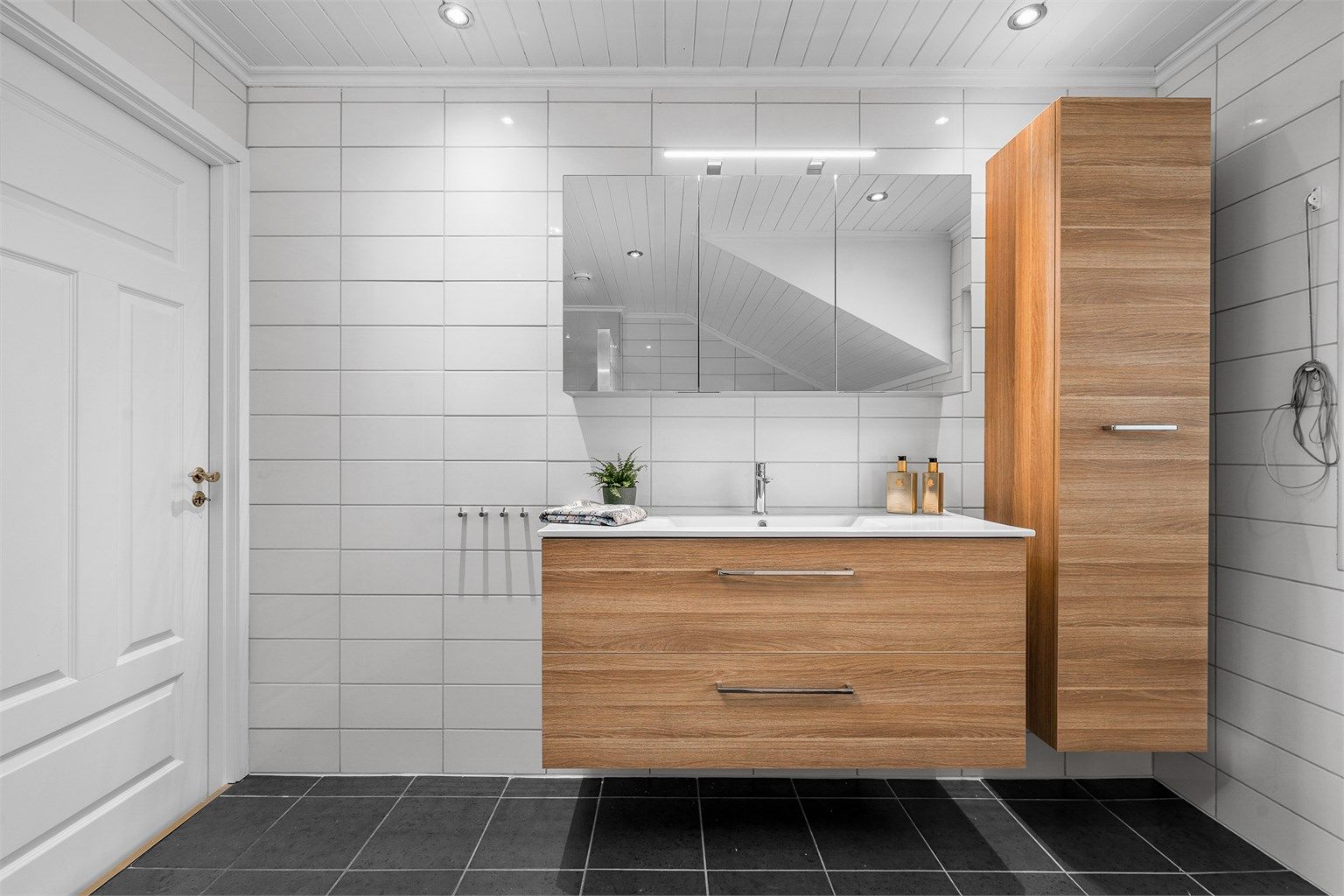 Baderomsinnredning fra Dansani med servant og speilskap, samt et praktisk høyskap for ekstra oppbevaring.