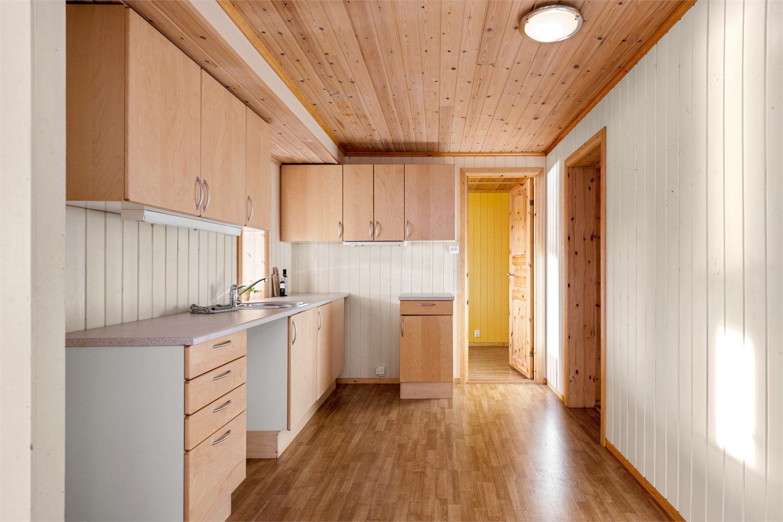 Kjøkkeninnredning i underetasjen med glatte finerfronter fra ca. 2002 med benkeplate av laminat. Kjøkkenventilator med avtrekk ut. 
(ikke byggemeldt og godkjent innredet)