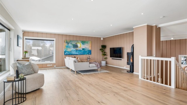 Stuen har en koselig peisovn som bidrar godt til både oppvarming og atmosfæren i rommet.