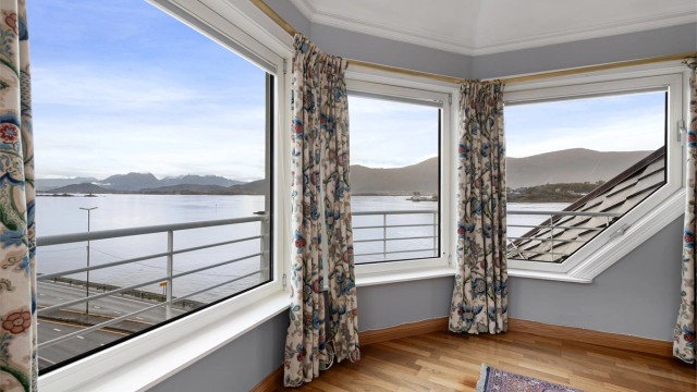 Store vindusflater gir et vidstrakt utsyn over fjorden og landskapet omkring.