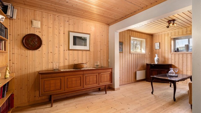 Innredet rom i kjeller med bokhylle, skjenk, sofa og stuebord