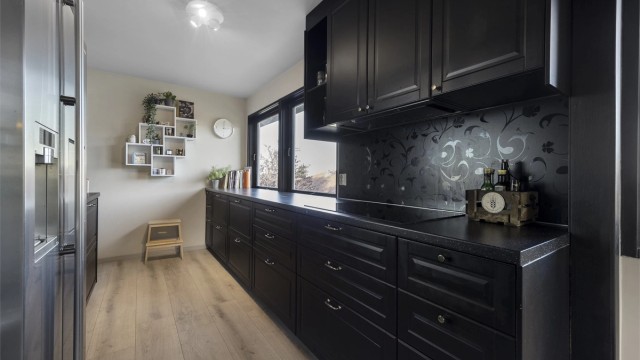 Kjøkkeninnredning med profilerte fronter, laminert benkeplate og integrert platetopp.