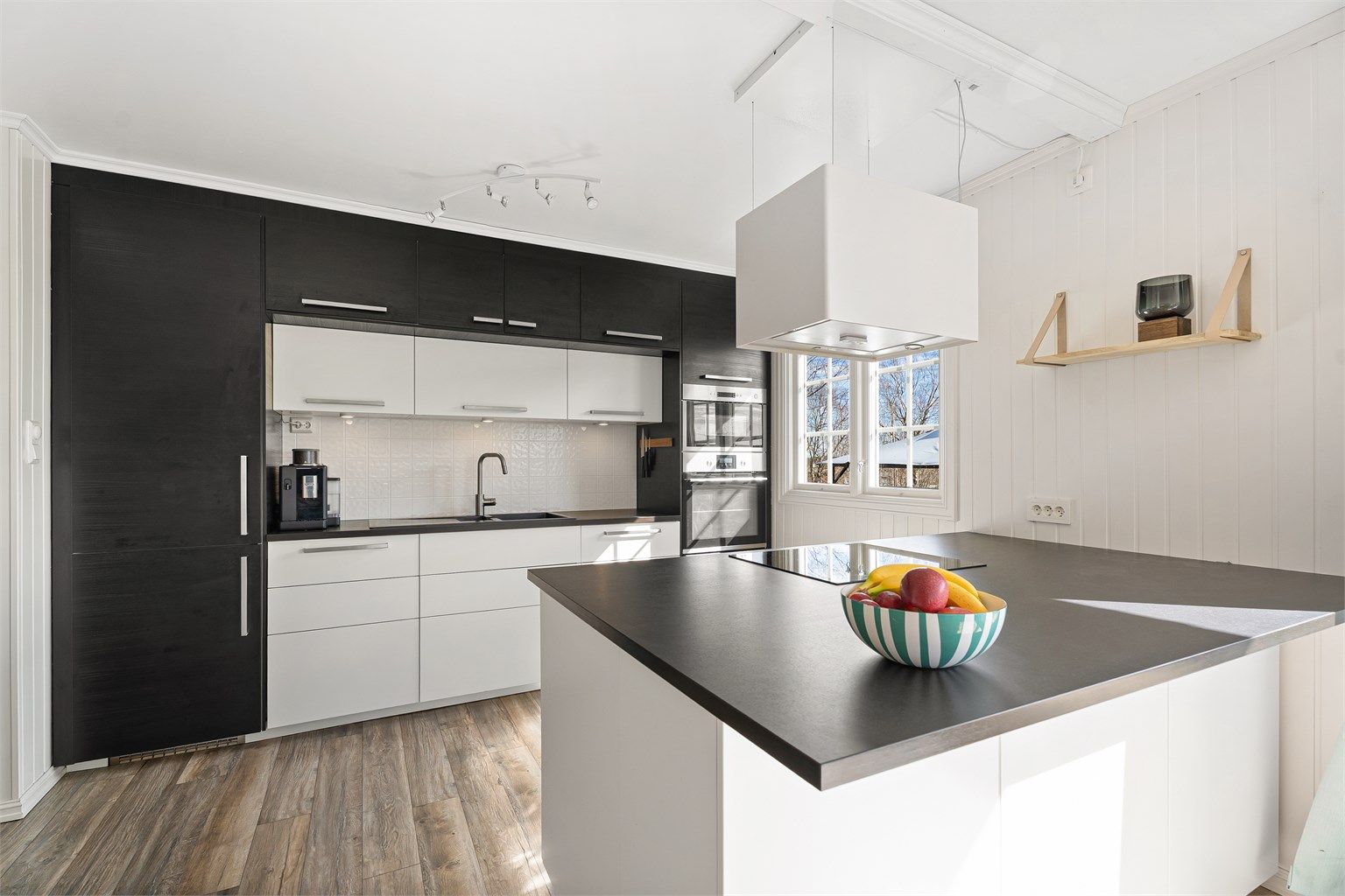 Pent åpent kjøkken med mye skapplass og kjøkkenøy med platetopp