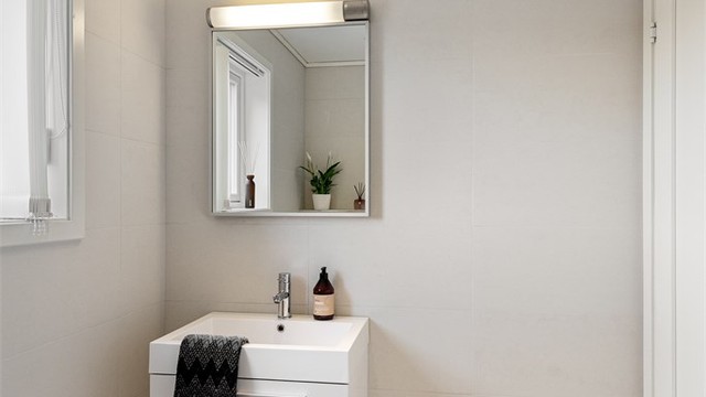 Servantinnredningen har en elegant, ovenpåliggende servant og speil med integrert belysning