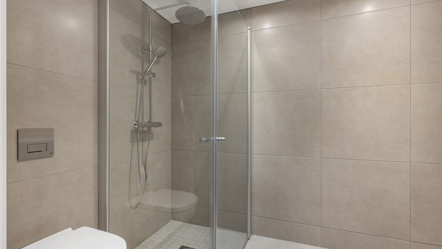 Plass og opplegg til vaskemaskin og tørketrommel. Badet består av veggmontert toalett, dusjdører i herdet glass, veggspeil med integrert belysning, baderomsinnredning med malte fronter og heldekkende servant