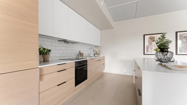 Kjøkkenet har slette fronter på skap og skuffer, og benkeplate av laminat med nedfelt oppvaskkum