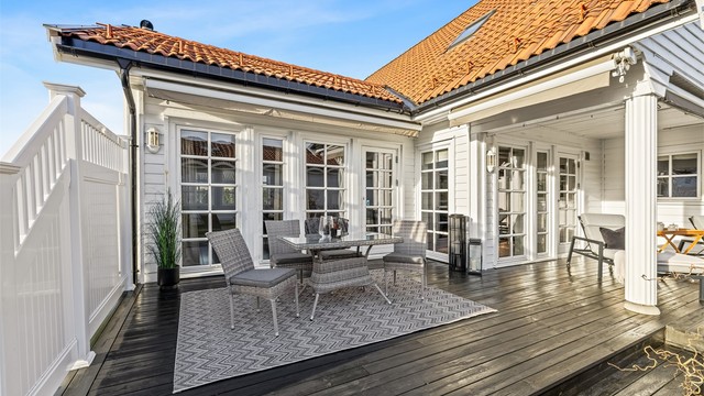 Den L-formede terrassen strekker seg langs to av husets fasader. Delvis overbygget og markisen gir en lun atmosfære.