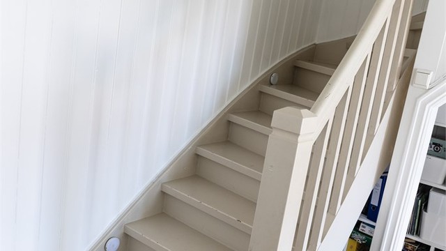 Innvendig trapp i trekonstruksjon leder opp til andre etasje.