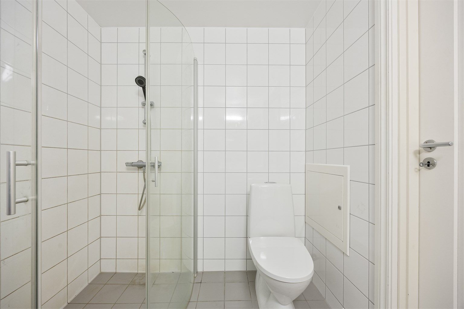 Dusjhjørne med innfellbare glassdører og opplegg for vaskemaskin.