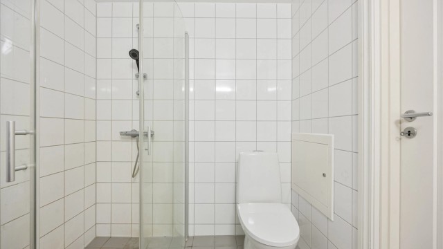 Dusjhjørne med innfellbare glassdører og opplegg for vaskemaskin.