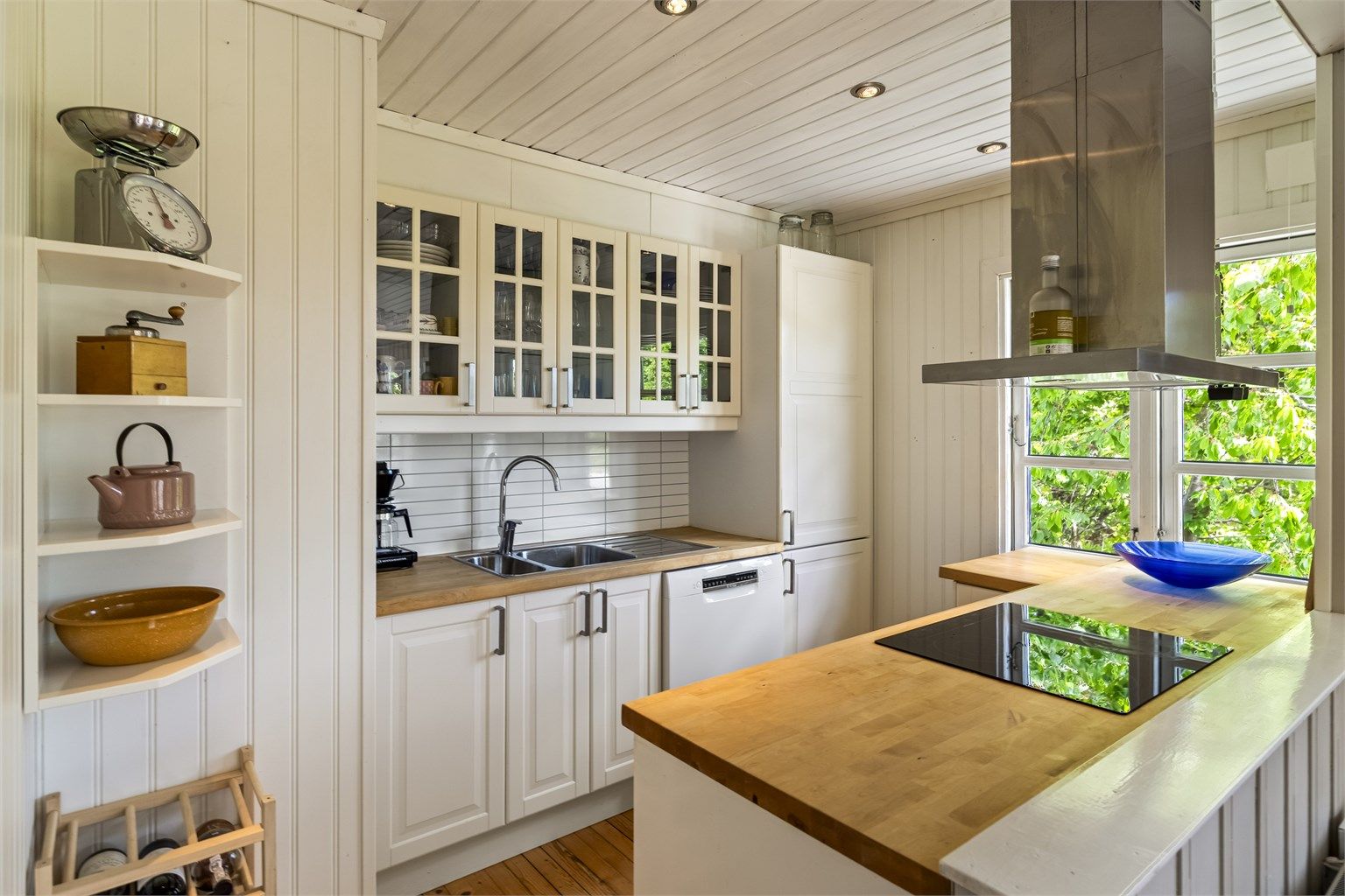 Kjøkkenet ligger i delvis åpen løsning mot stuen og har lys innredning med profilerte fronter og benkeplate i tre. Det er montert Kitchen Board-plater mellom benkeplate og overskap.