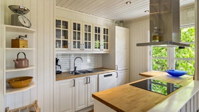 Kjøkkenet ligger i delvis åpen løsning mot stuen og har lys innredning med profilerte fronter og benkeplate i tre. Det er montert Kitchen Board-plater mellom benkeplate og overskap.