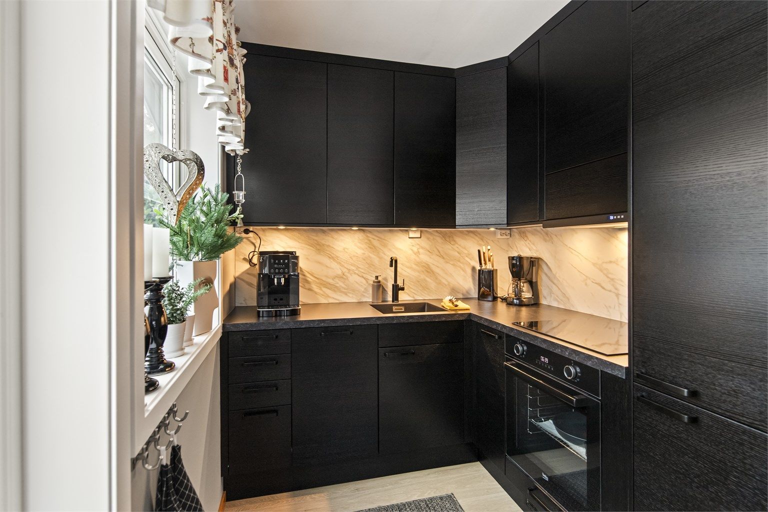 Lekkert og tidløst Epoq kjøkken med integrerte hvitevarer og splashboard på vegg