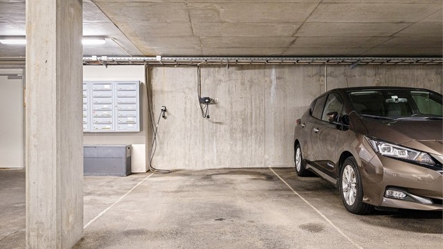 Parkeringsplassen er utstyrt med elbillader. Praktisk plassering like ved postkasser og dør til sameiet.