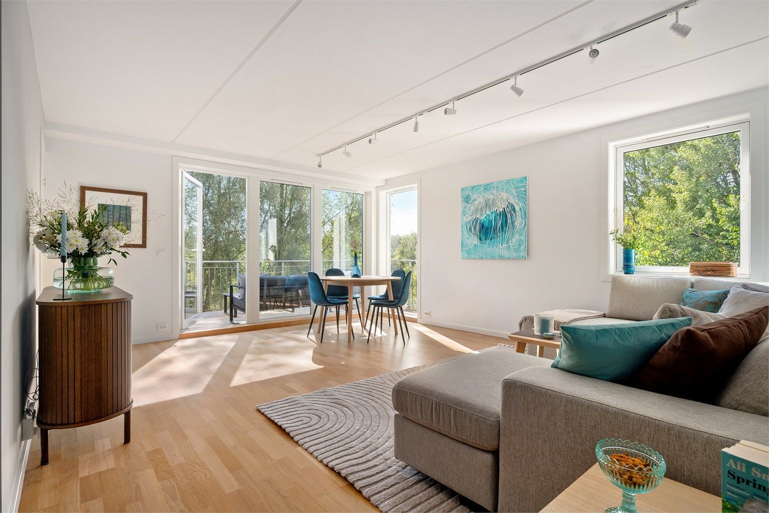 Luftig og svært lys stue med store vindusflater mot det grønne parkdraget langs Akerselva. 