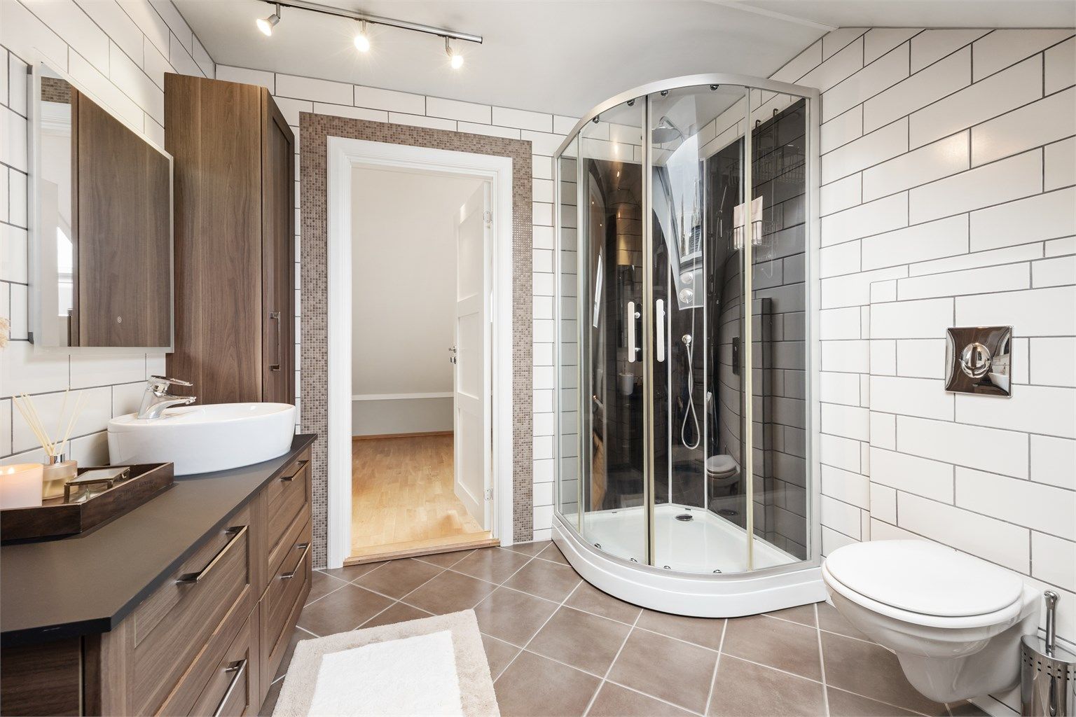 Badet har servantinnredning, vegghengt toalett og dusjkabinett.
