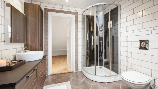 Badet har servantinnredning, vegghengt toalett og dusjkabinett.
