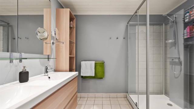 Fliser på gulv med gulvvarme, flislagte vegger i dusjsonen, malte tapetserte veggflater og panelbord i himling med downlights
